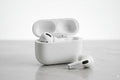 White wireless earbuds with charging case on a light gray surface
